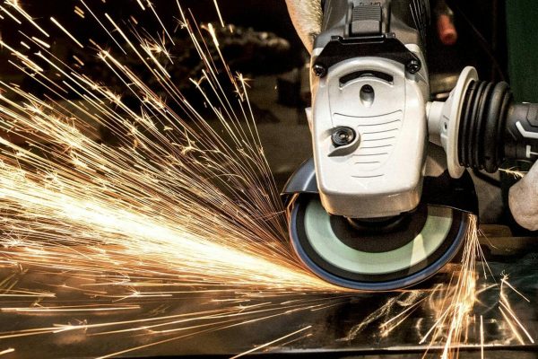 Close-up of a skilled worker using a grinder with sparks flying in a metal workshop.